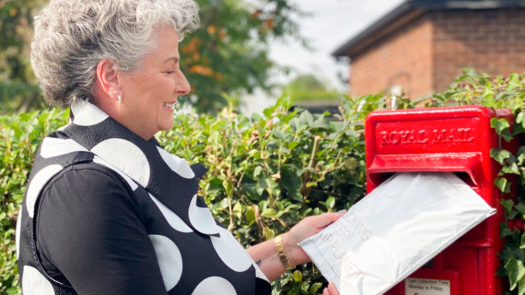 Photo showing Maxine Laceby posting a white Absolute Collagen recycling bag into a postbox